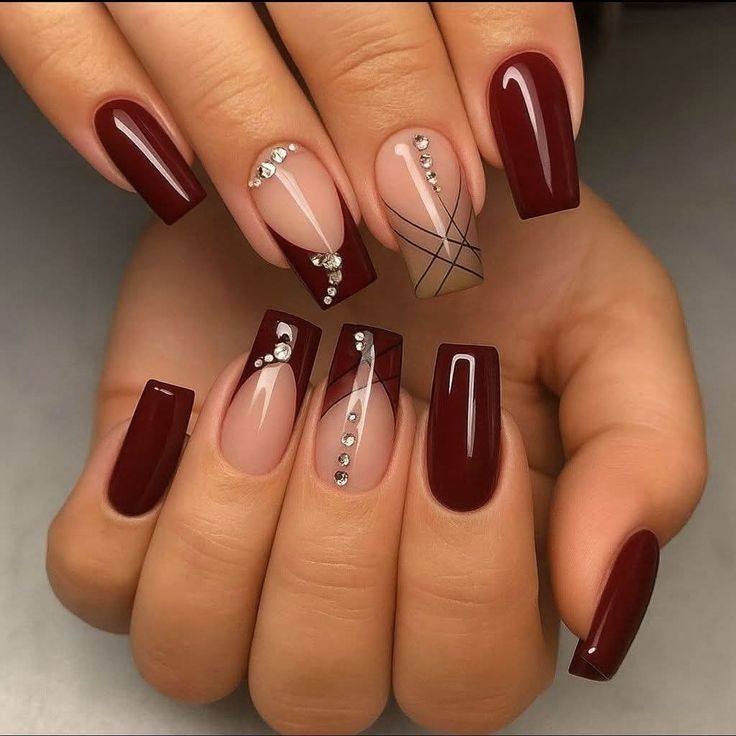 Elegant square-shaped acrylic nails featuring deep burgundy polish, nude accent nails, sparkling rhinestones, and geometric line details for a luxurious manicure design.