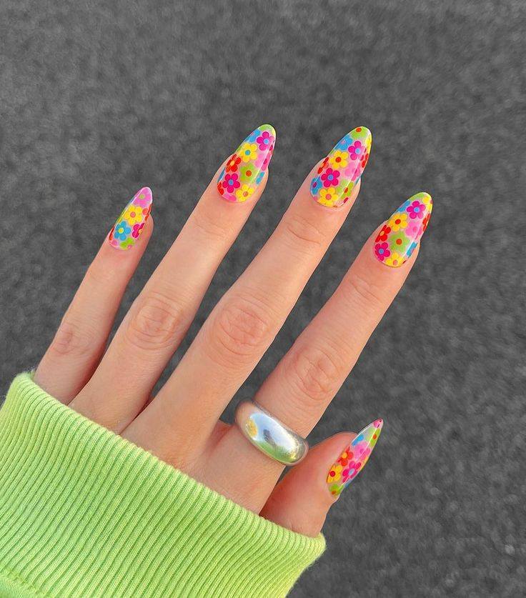 Colorful almond-shaped nails featuring bright floral patterns in pink, yellow, blue, and orange, creating a fun and vibrant summer nail art design.