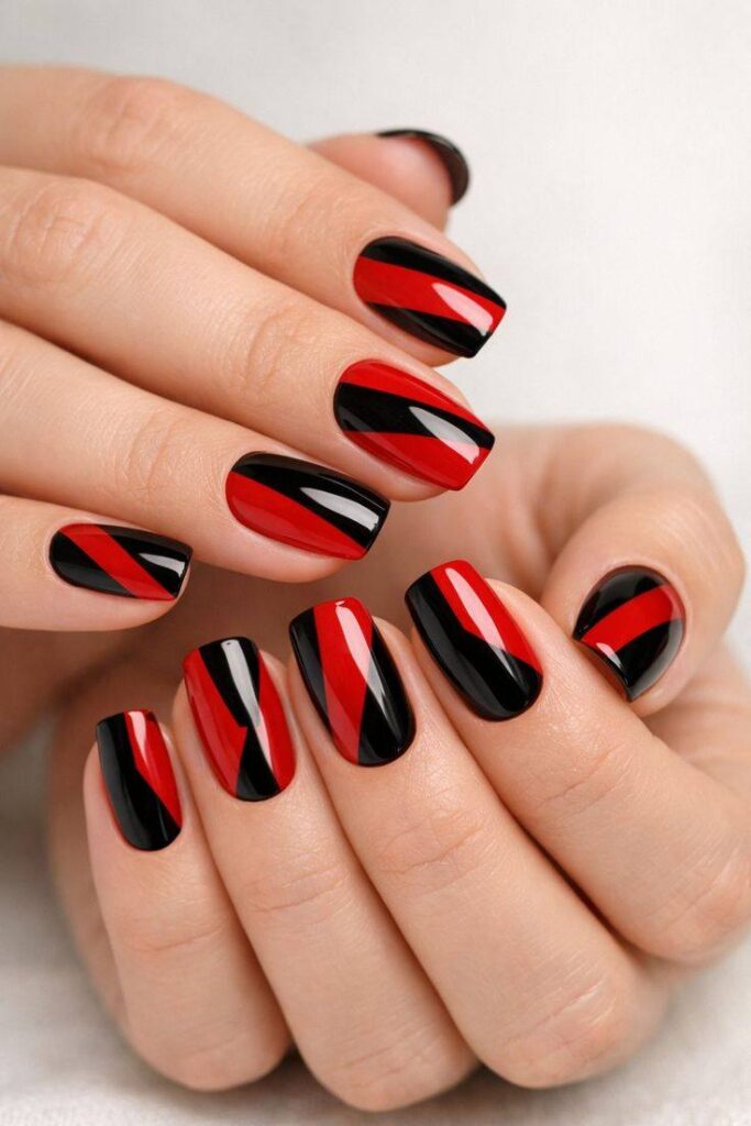 Glossy square-shaped nails featuring bold red and black geometric color-block patterns, creating a modern, edgy, and stylish nail art design.