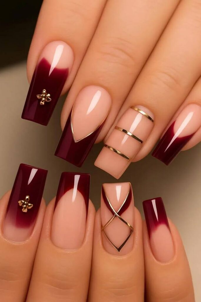 Elegant square-shaped nails featuring burgundy ombré French tips, gold metallic accents, geometric nail art details, and a glossy nude base for a luxurious manicure design.