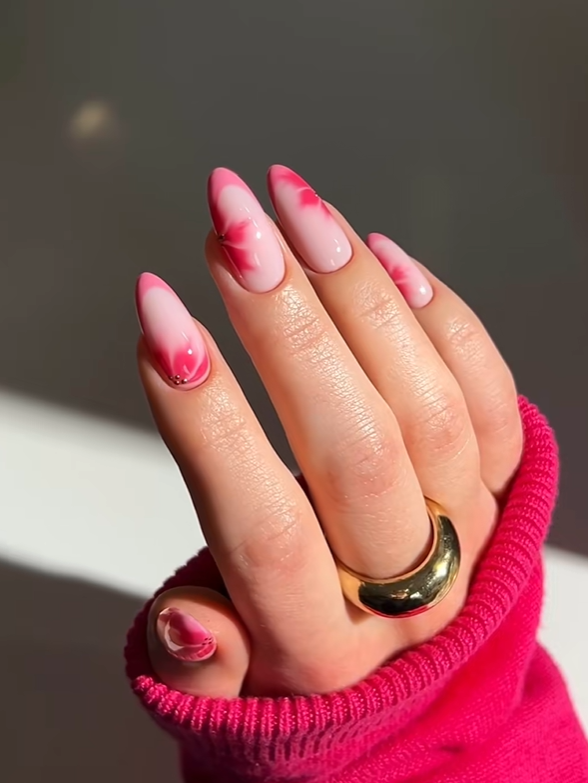 Glossy almond nails with soft pink aura-style airbrush designs on a nude base, creating a feminine and elegant minimalist manicure look.