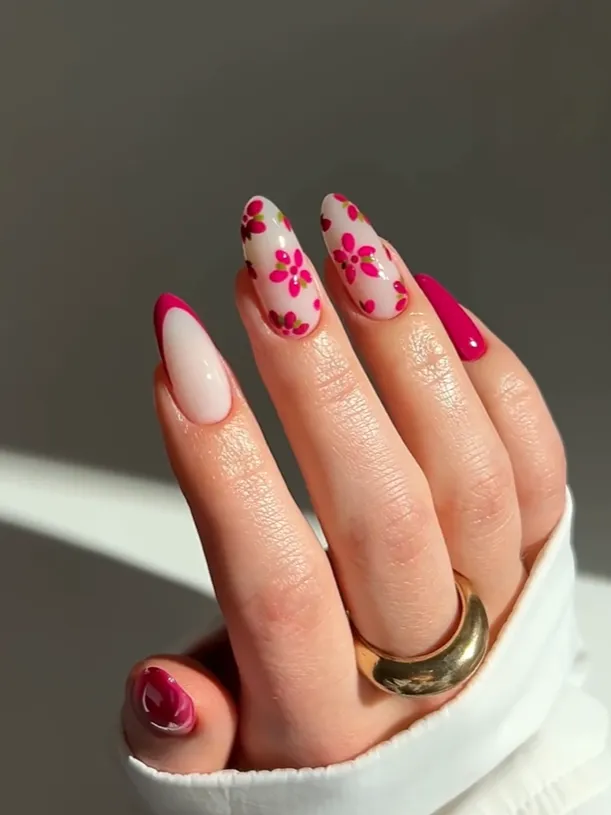Pink floral nail art with glossy almond-shaped acrylic nails, featuring cute flower designs, bright pink French tips, and trendy feminine manicure inspiration.