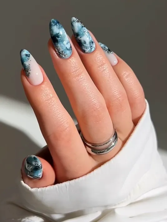Ocean Marble Blue Nails Blue marble acrylic nails with glossy ocean-inspired nail art design, featuring smoky swirl patterns, white accents, and elegant almond-shaped winter manicure inspiration.