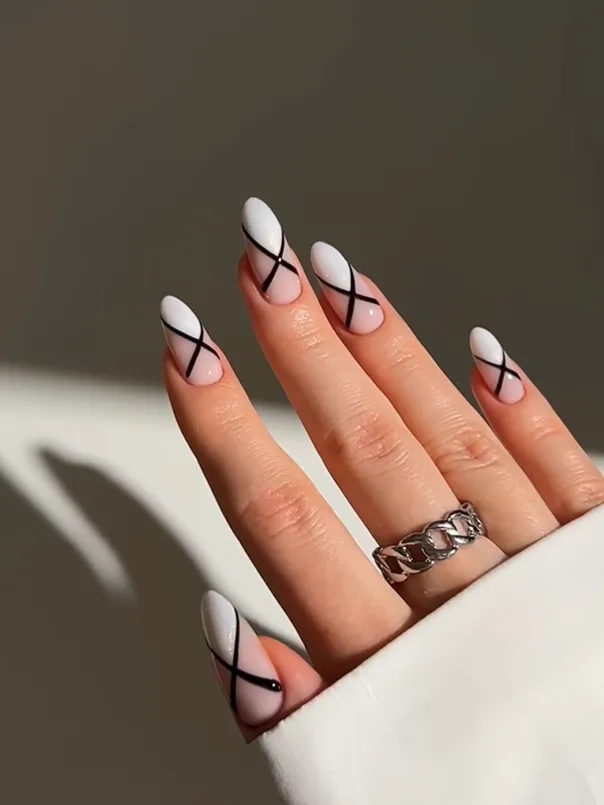 Black and White Ribbon Nails Black and white minimalist nail art with abstract ribbon line details on almond-shaped acrylic nails, featuring elegant glossy French tip manicure and modern classy nail design inspiration.