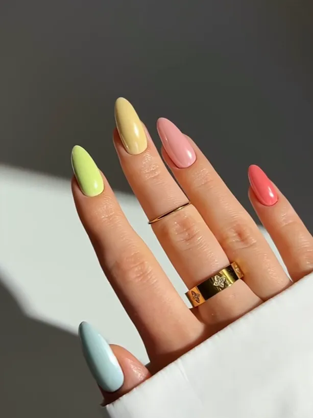 Pastel rainbow acrylic nails with glossy almond-shaped manicure design, featuring soft yellow, pink, green, coral, and blue nail colors for trendy spring and summer nail art inspiration.