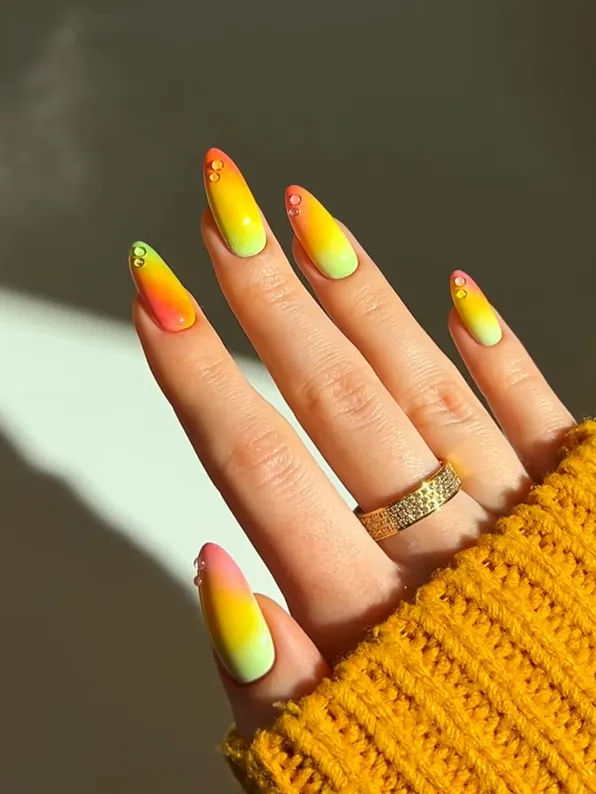 Sunset Ombre Neon Nails Neon sunset ombre nails with bright yellow, orange, and green acrylic nail art design, featuring glossy almond-shaped nails and colorful summer manicure inspiration with crystal accents.