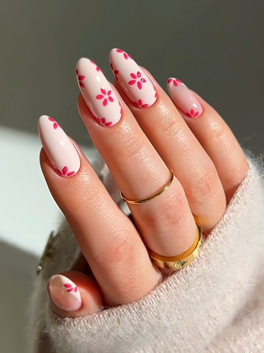 Minimal pink daisy flower nails with soft blush polish and delicate floral nail art on almond-shaped acrylic nails.