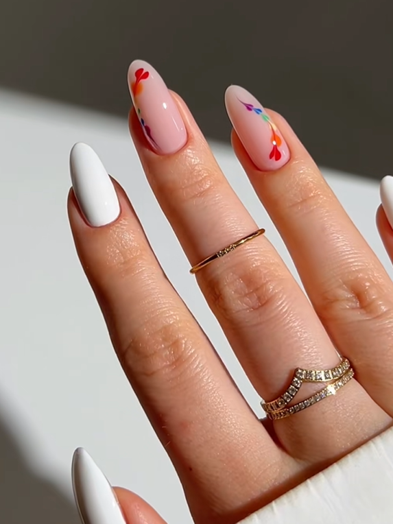 Elegant almond-shaped nails featuring a soft pink and white manicure with colorful floral accents, creating a minimalist and feminine nail art design.